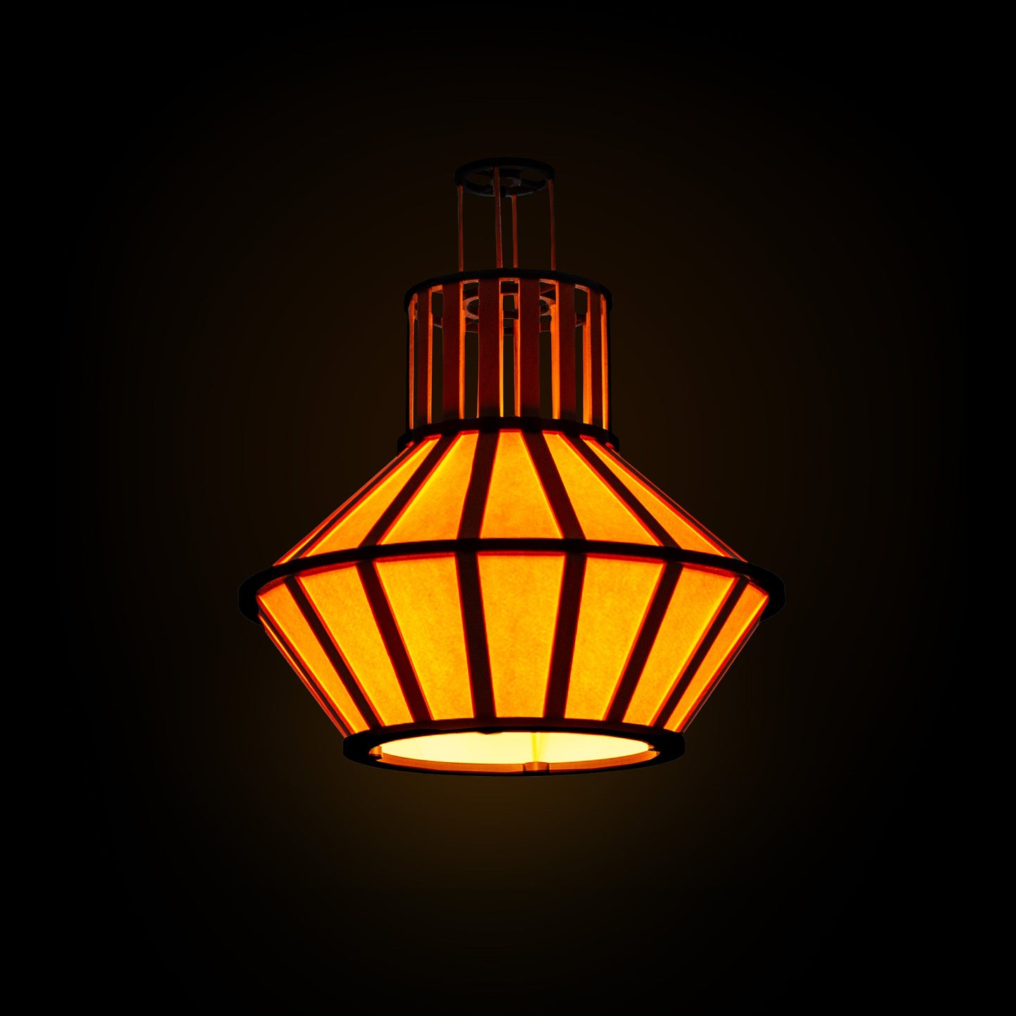 Hängande design-lampskärm i gult med svarta delar och trädetaljer, lyser mot en mörk bakgrund