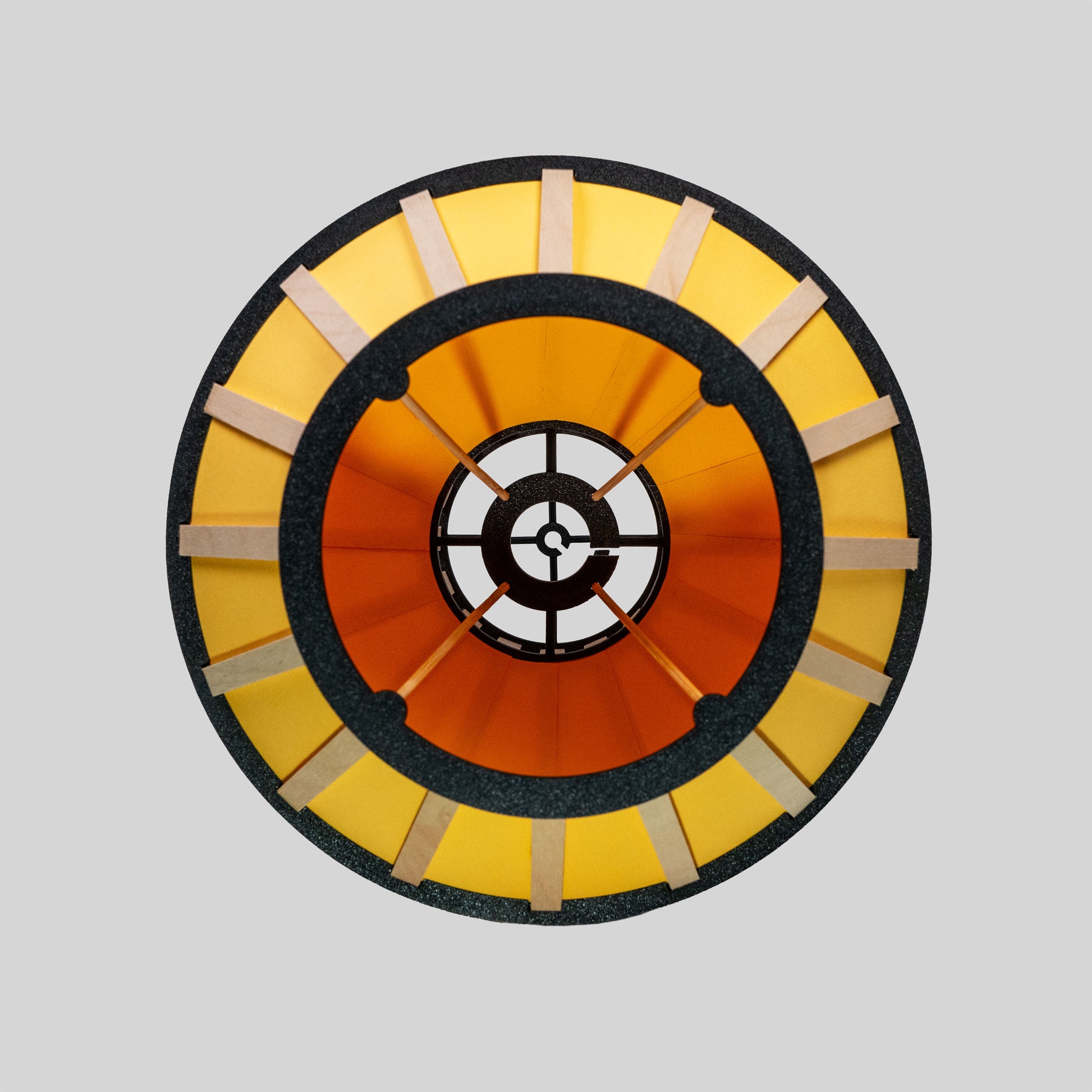 Design-lampskärm i gult med svarta delar och trädetaljer fotad underifrån